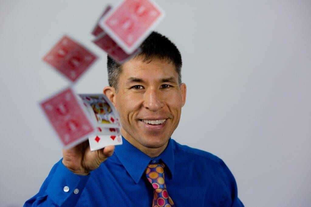 A man in a blue shirt and tie is throwing playing cards in the air