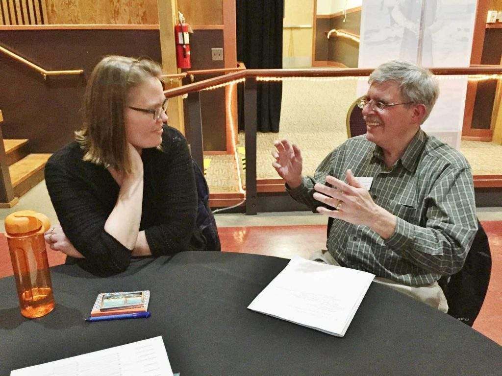 A man and a woman are sitting at a table talking