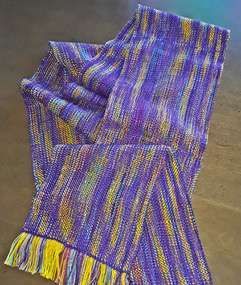 A purple and yellow scarf is sitting on a wooden table.