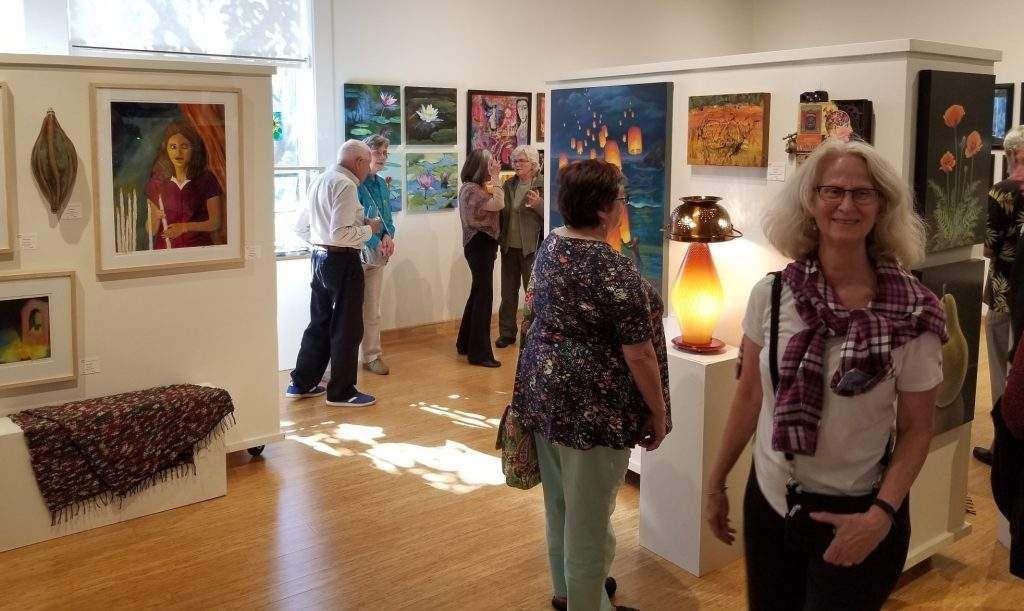 A group of people are standing in a room looking at paintings.