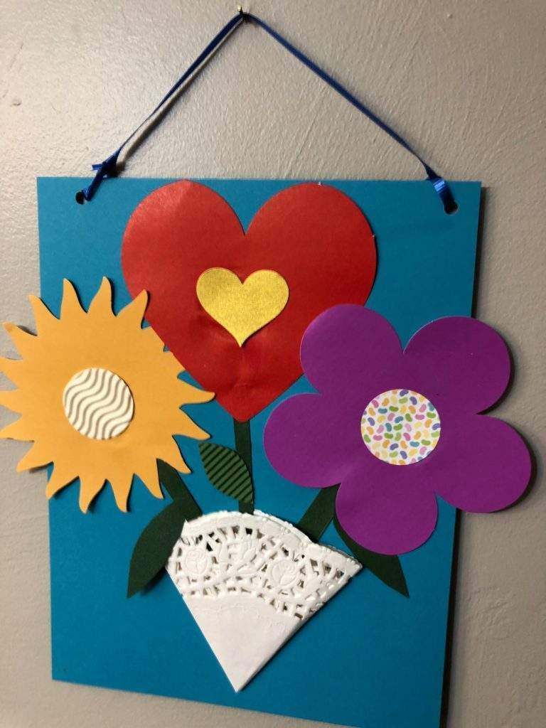 A blue board with paper flowers and hearts on it