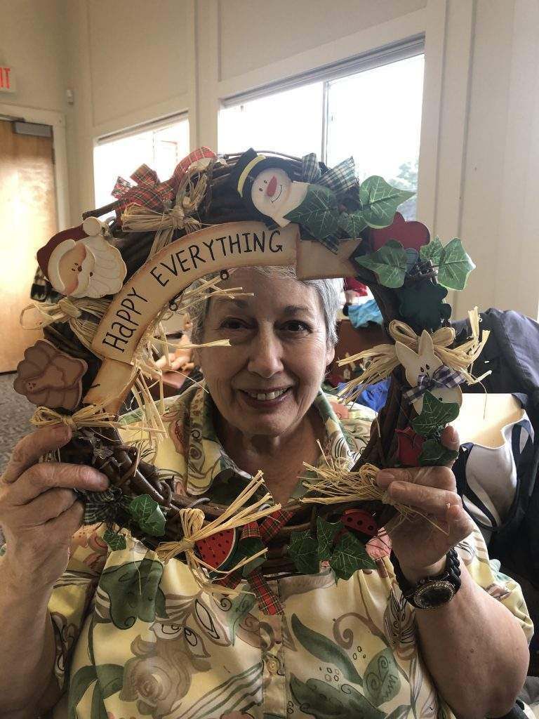A woman is holding a wreath that says `` happy everything ''.