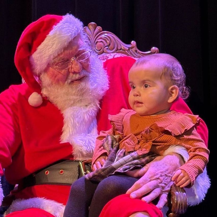 A man in a santa suit is holding a baby in his lap.