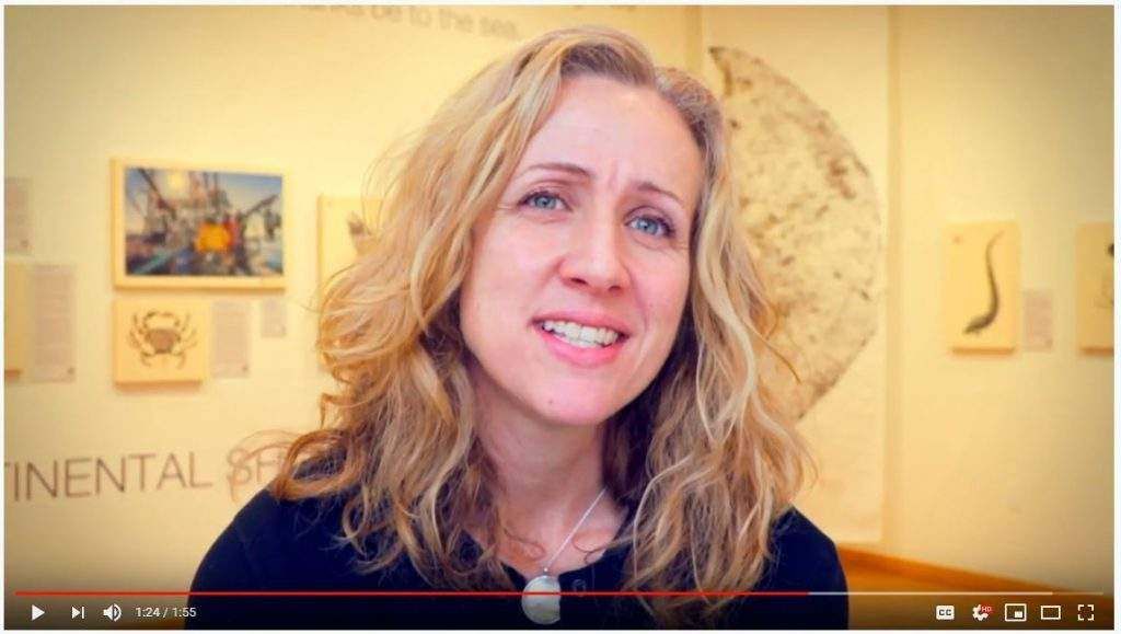 A woman is smiling in front of a wall that says mental health