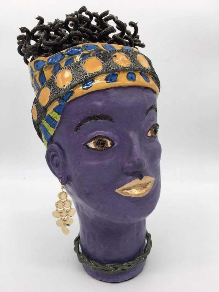 A purple ceramic head with a yellow headband and earrings