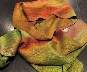 A colorful scarf is sitting on a wooden table.