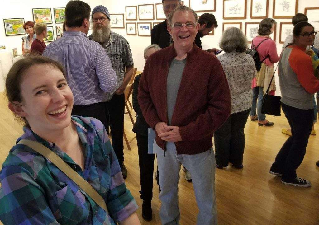 A woman in a plaid shirt is smiling in a crowd of people