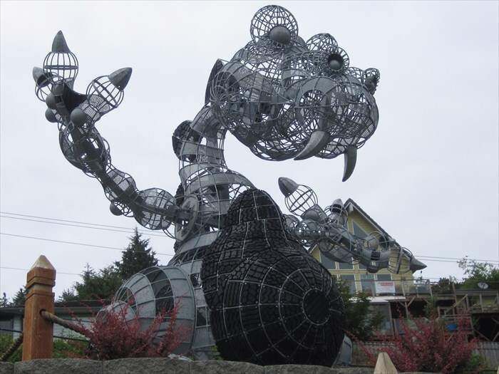 A large metal sculpture of a dragon is in front of a house