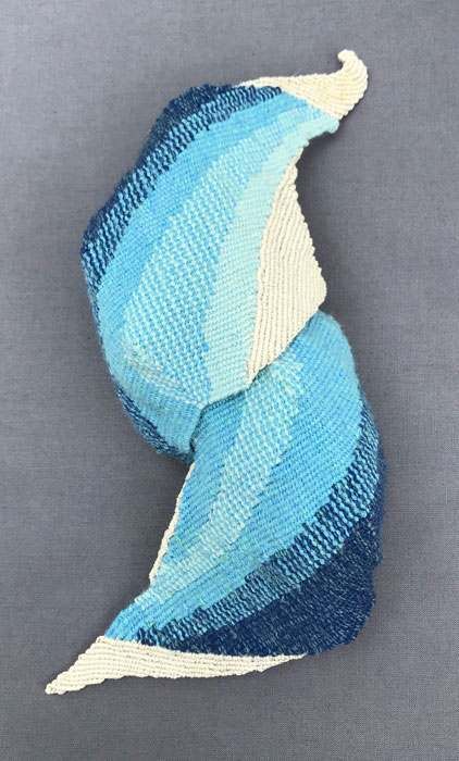 A blue and white knitted object is sitting on a gray surface.