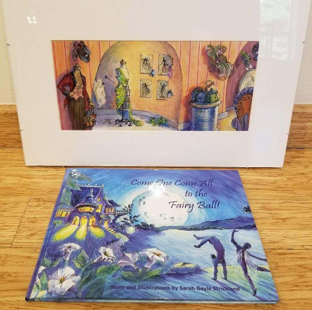 A book and a picture are sitting on a wooden table.
