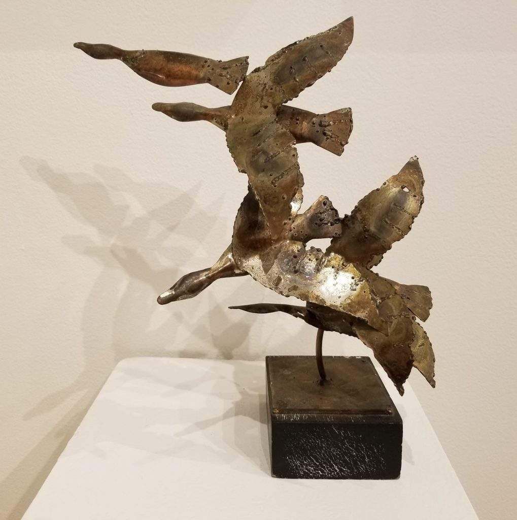 A statue of three birds flying in the air
