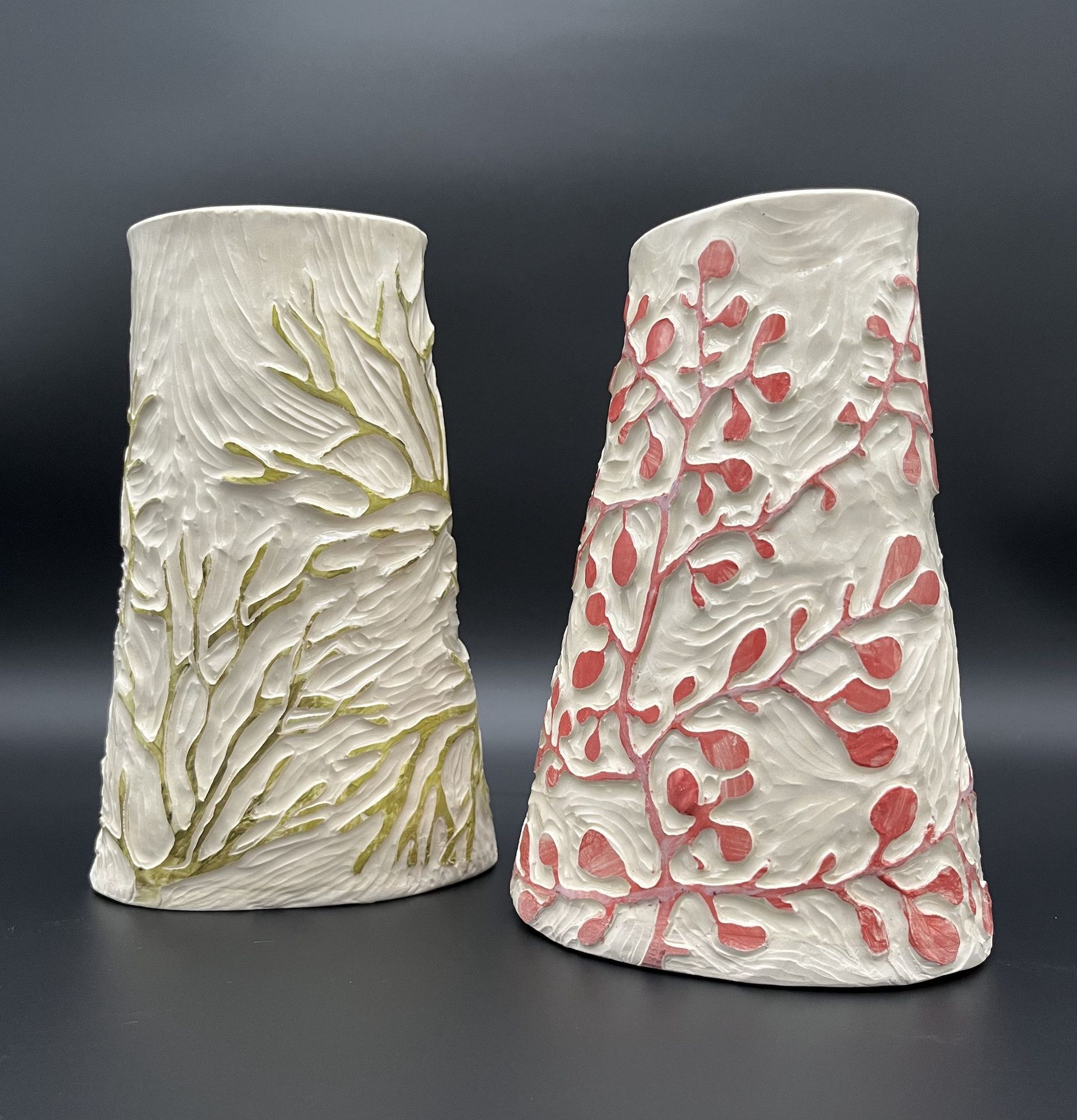 Two vases with different designs on them are sitting next to each other on a table.