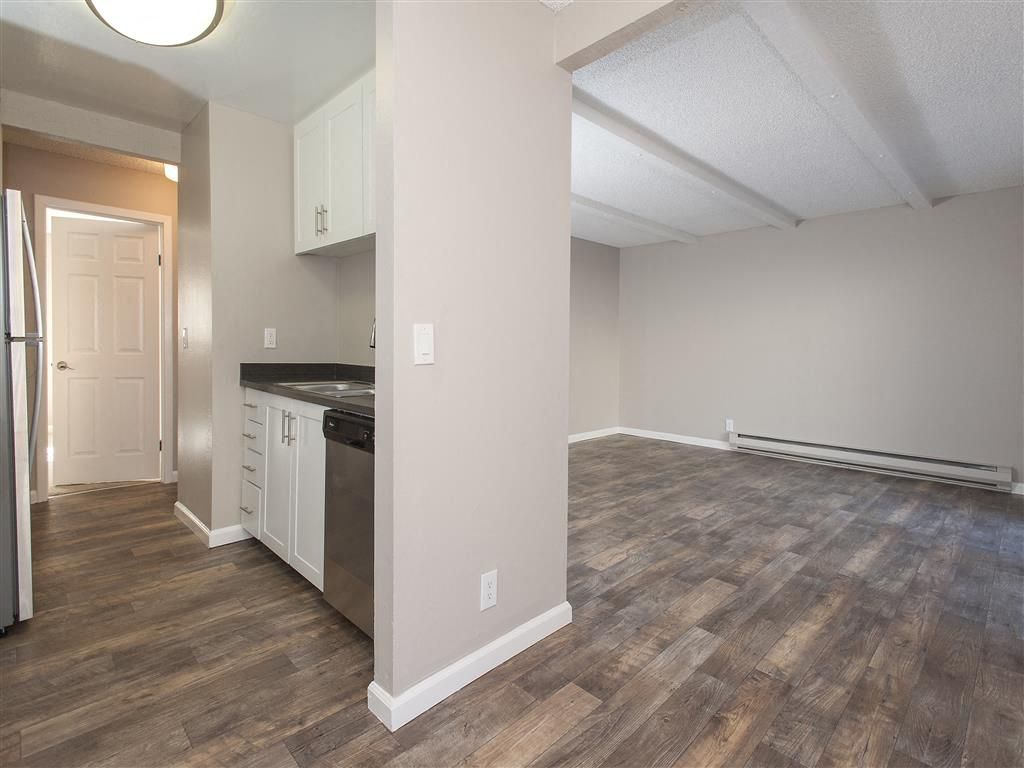 Open kitchen with white cabinets, stainless steel appliances, and a spacious living area.