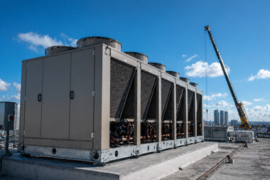 Large rooftop HVAC unit beside a crane under a blue sky