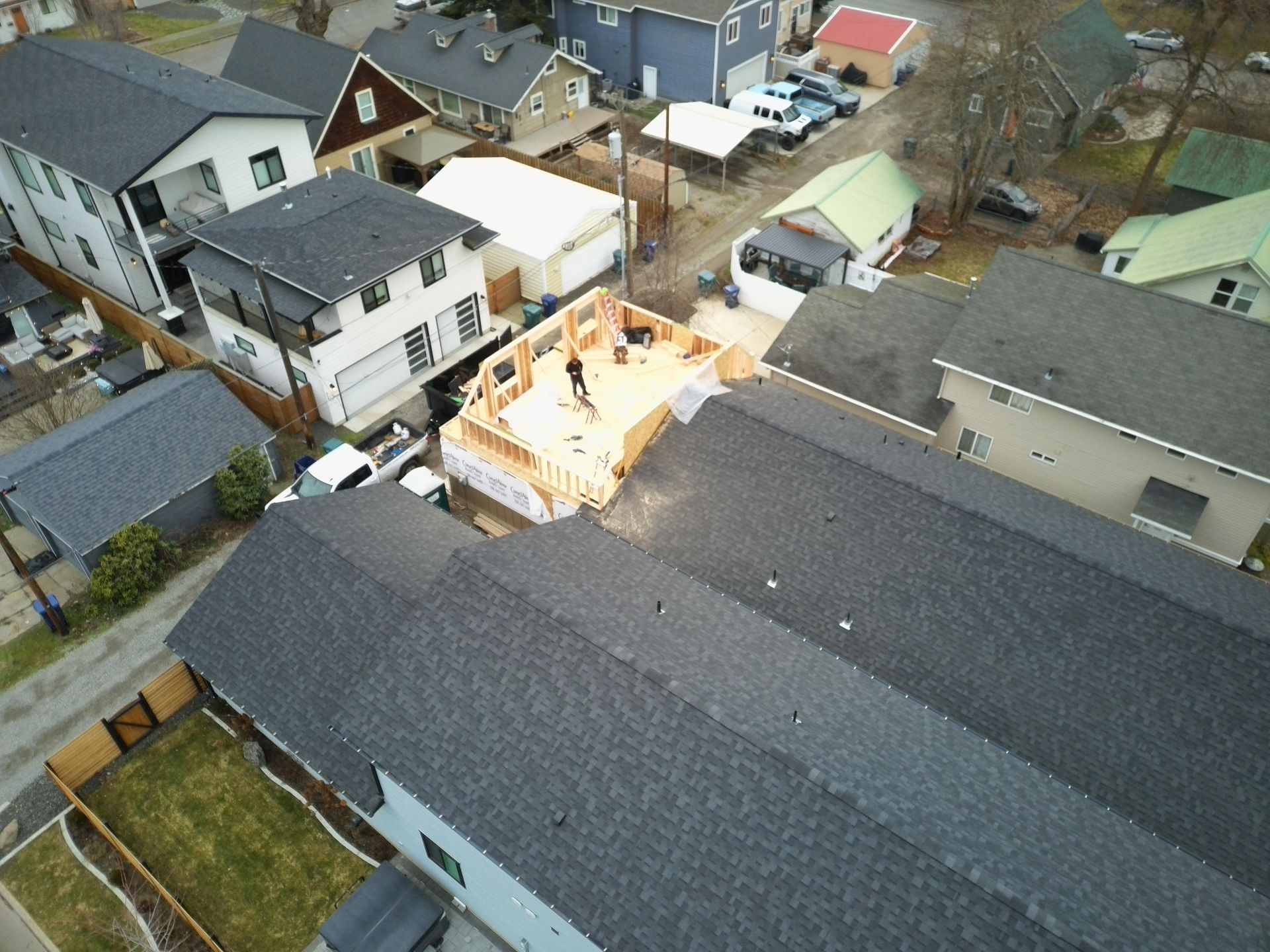 Aerial view of a home construction site surrounded by houses with gray roofs.