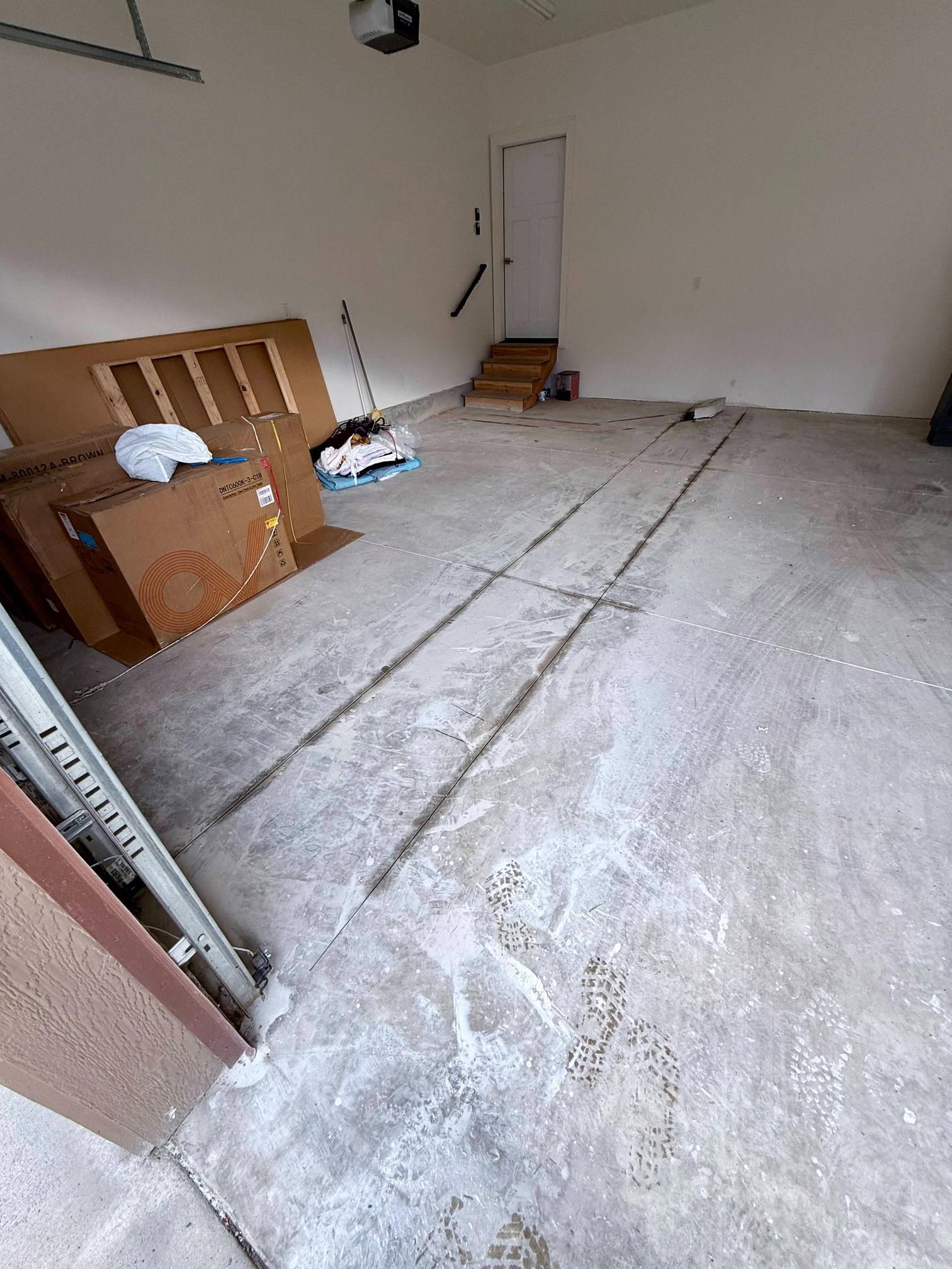 Empty garage with concrete floor, cardboard boxes, and a door in the back.
