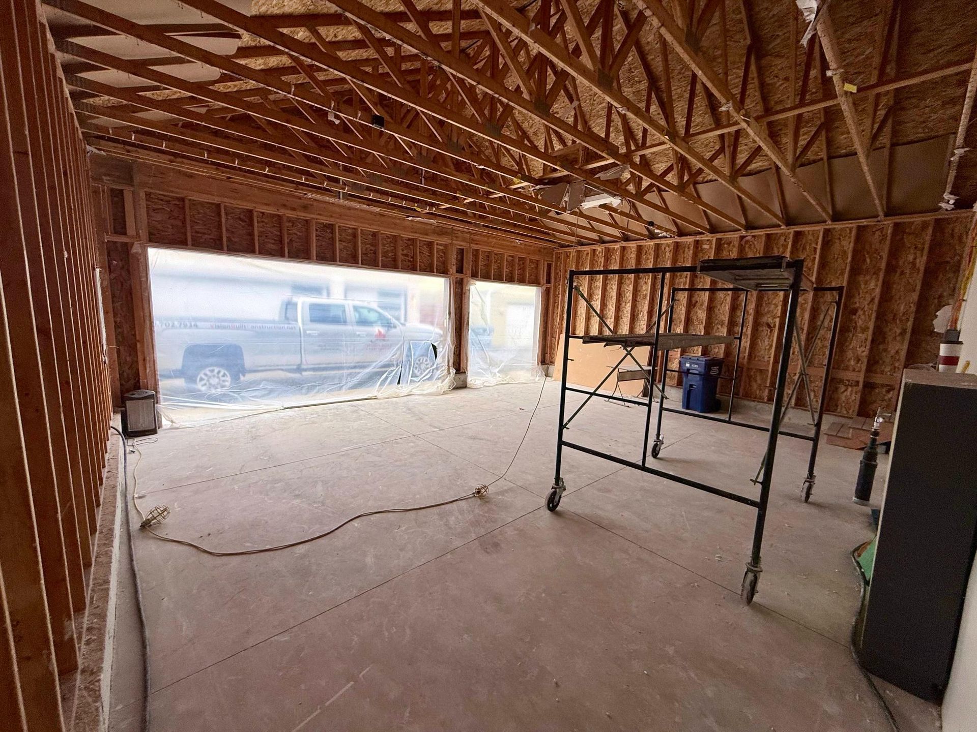 Interior of a garage under construction with wooden framing and concrete floor.