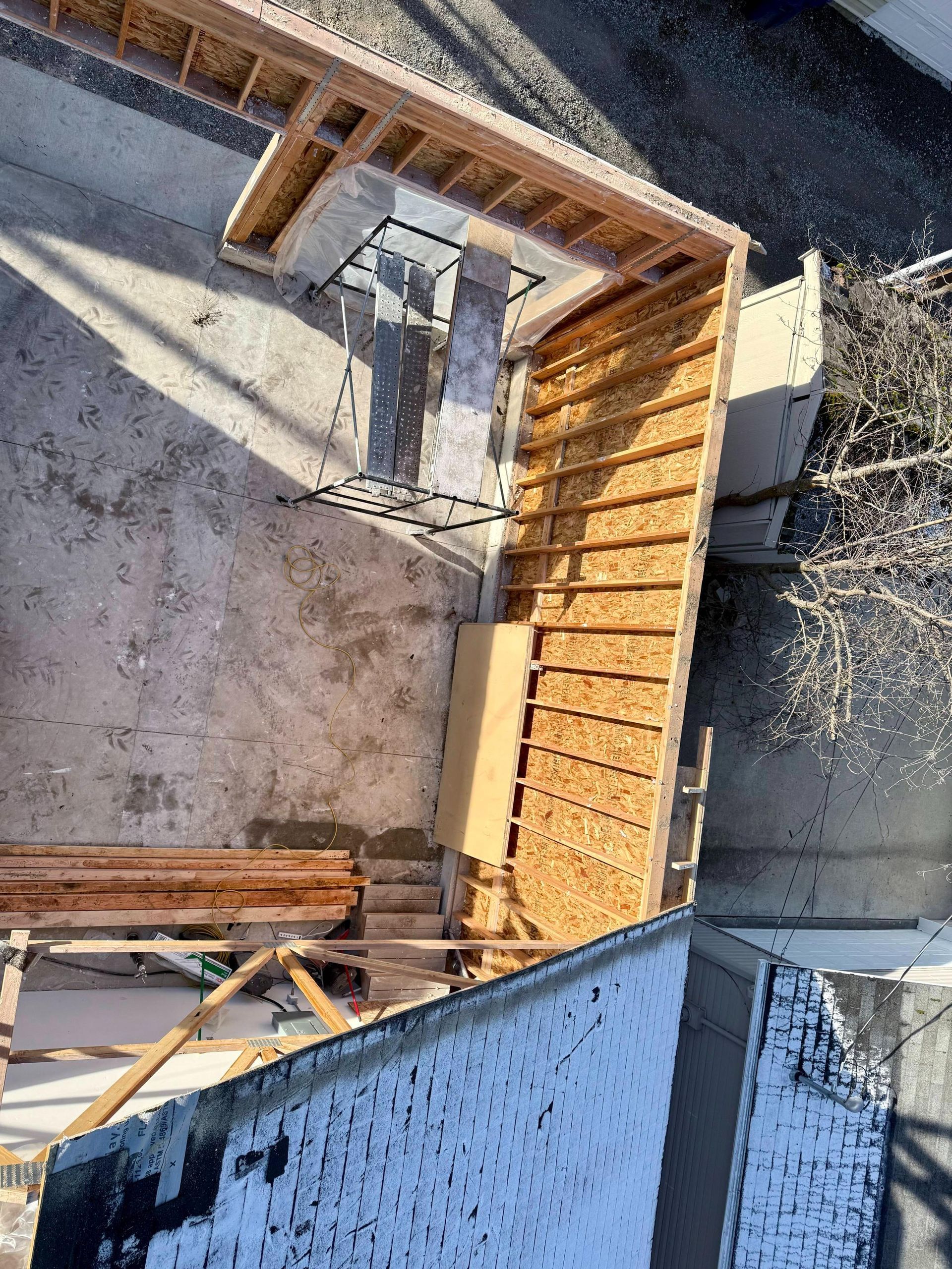 Overhead view of a construction site with wooden framing for stairs and a concrete platform.