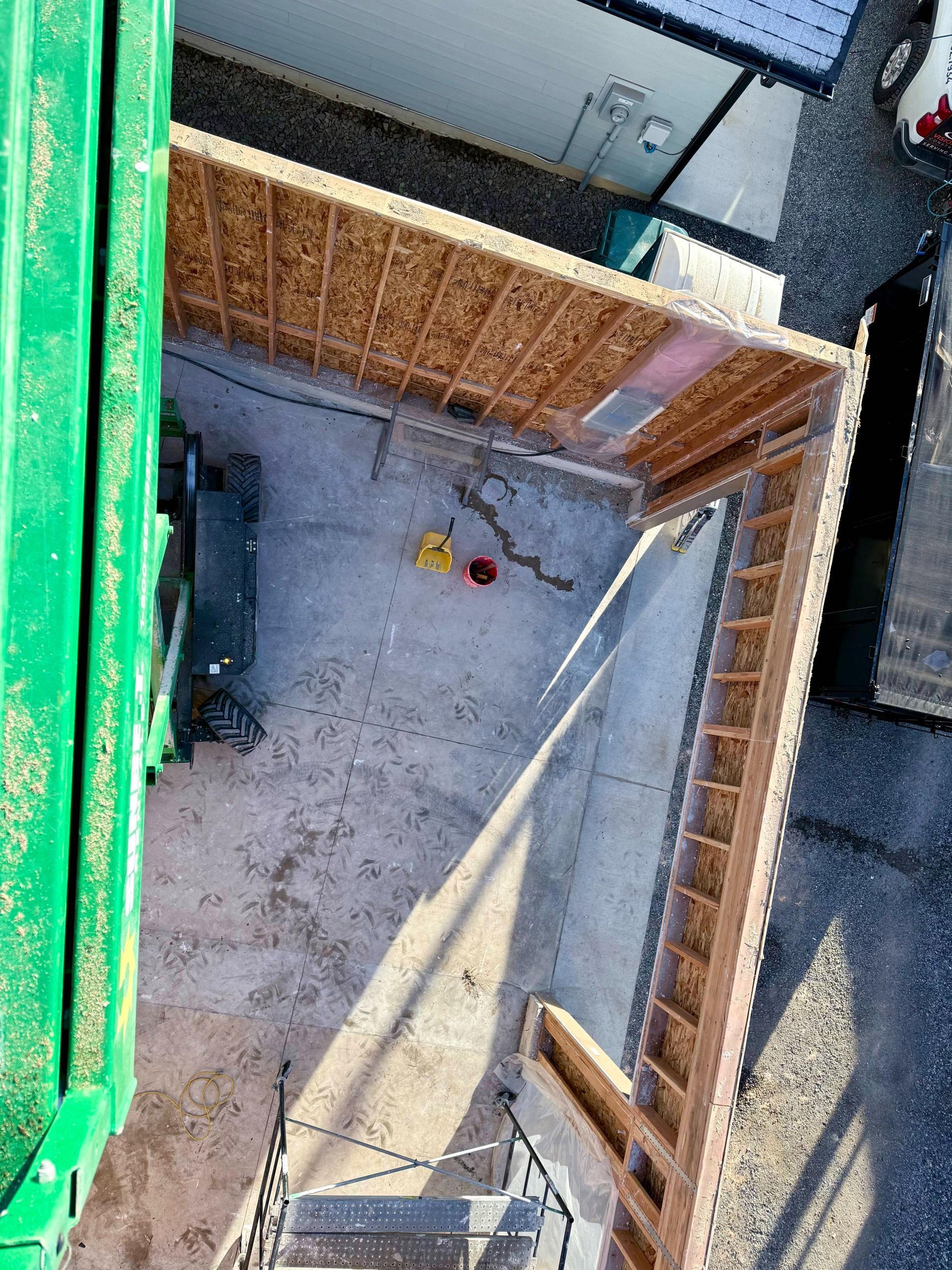 Overhead view of a construction site with exposed wooden framing and concrete ground.