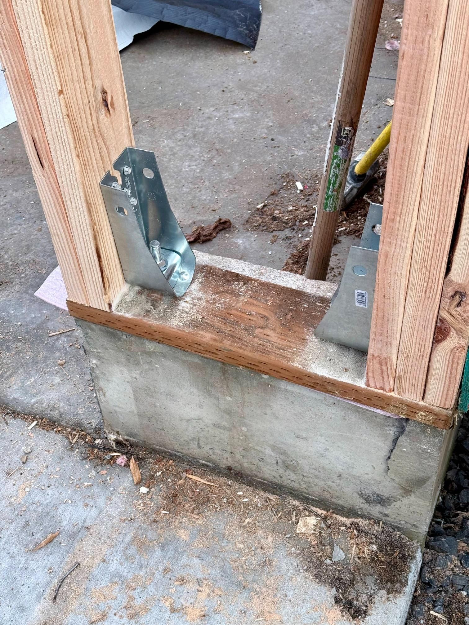 Framing attached to concrete base with metal brackets.