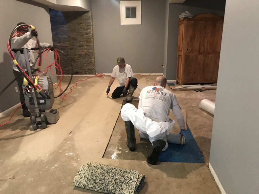 A group of men are working on a basement floor.