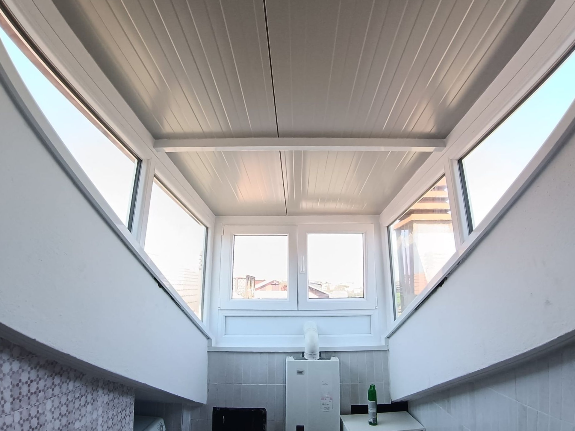 Una piccola stanza con pareti bianche e finestre. Soffitto e finiture bianche. Le finestre offrono una vista sull'esterno.