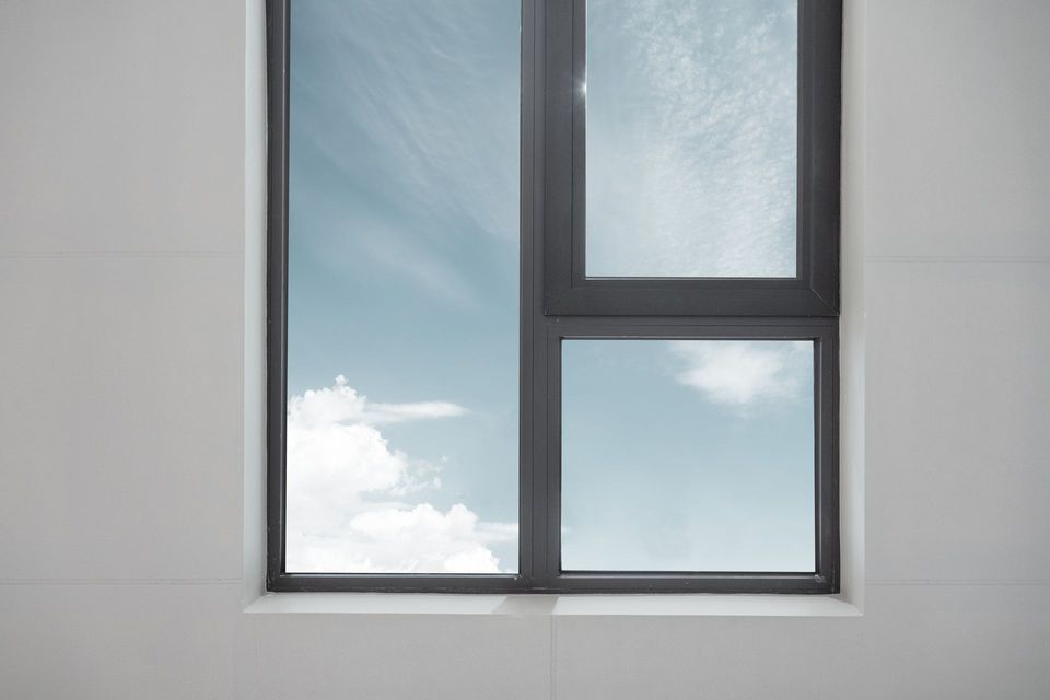Luminoso soggiorno con porte scorrevoli che si aprono su un balcone con vista sugli alberi verdi; arredamento moderno.