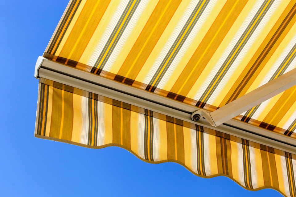 Tenda a strisce gialle e bianche contro un cielo azzurro terso.