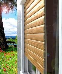 Vista esterna: persiane in legno che coprono parzialmente una finestra; è visibile una scena esterna soleggiata.