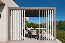 Pergola grigia con doghe verticali bianche, parzialmente aperta, che rivela un'area salotto all'aperto.