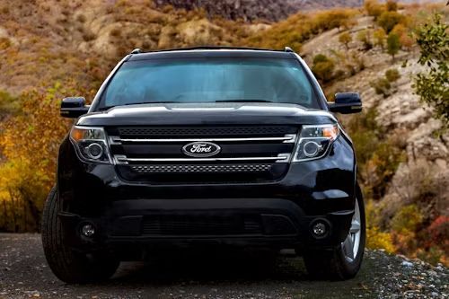 Black Ford Explorer SUV parked on a dirt road, mountain background with autumn foliage.