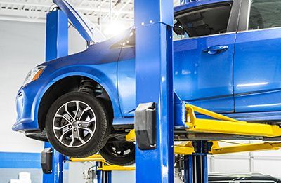 A blue car is sitting on a lift in a garage.
