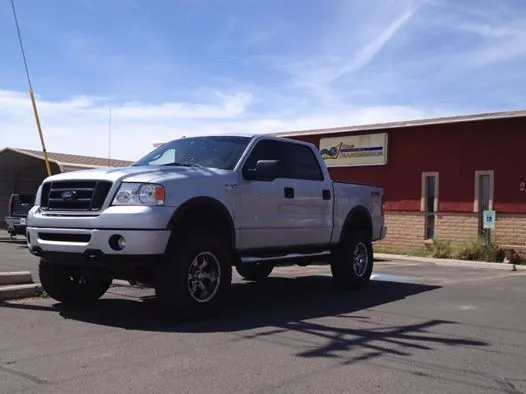 A silver truck is parked in front of a red building