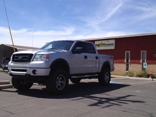 A white truck is parked in front of a red building