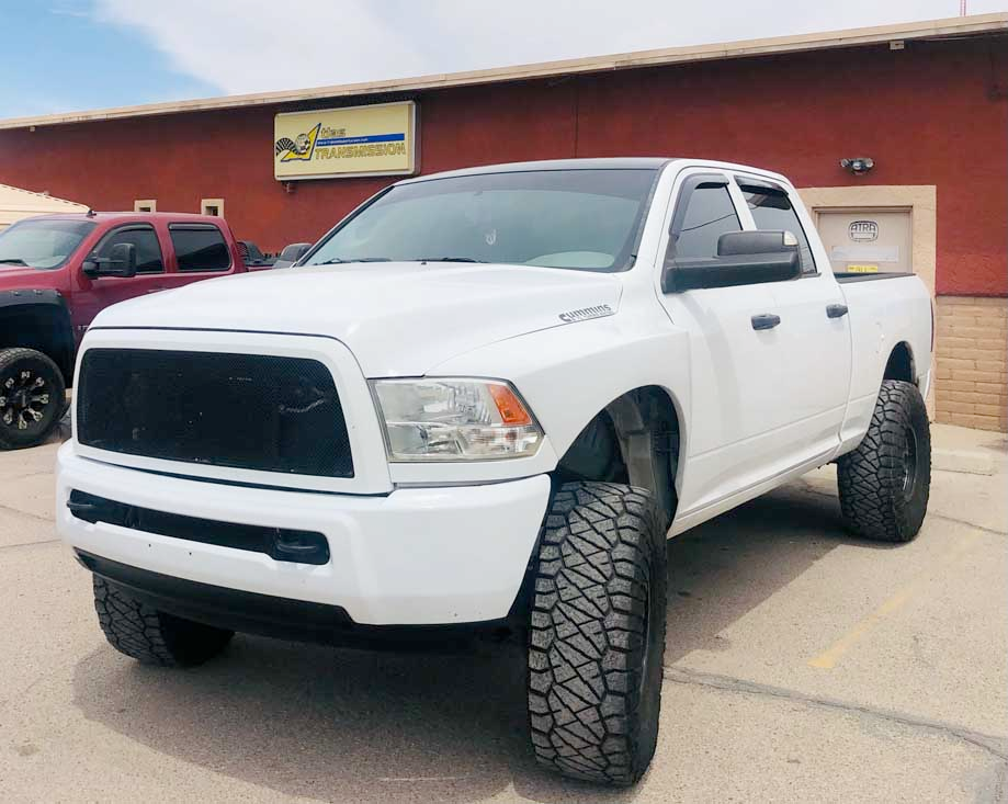 A white dodge ram truck is parked in front of a building.