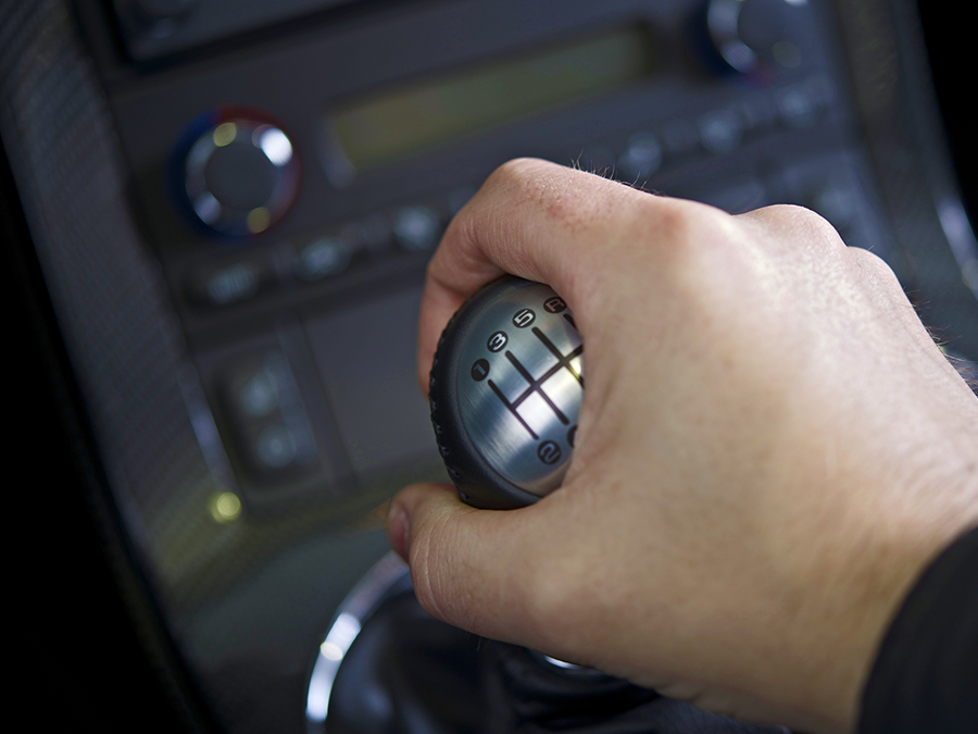 A close up of a person 's hand holding a gear shift in a car.