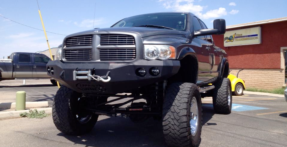 A black truck is parked in a parking lot in front of a building.