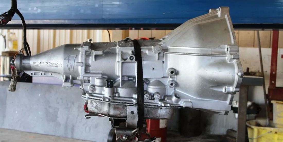 A silver gearbox is sitting on a table in a garage.