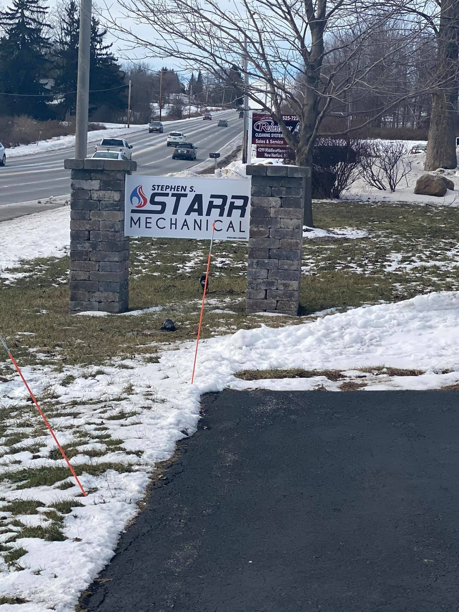 Sign for Starr Mechanical between stone pillars, set in snow with a road in the background.