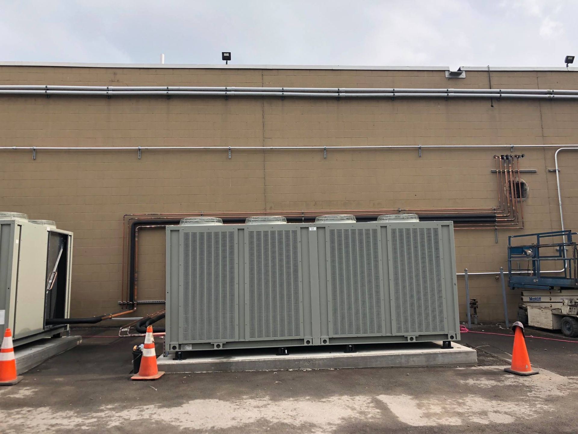 HVAC units installed outside of a building with safety cones.