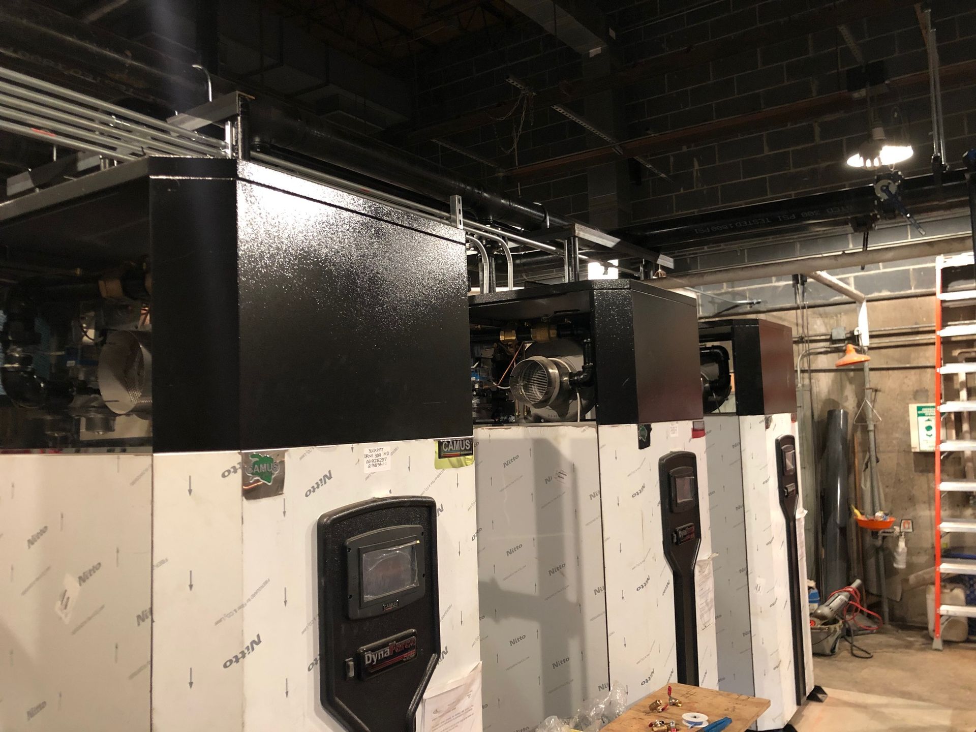 Electric vehicle charging stations in an industrial setting, with black panels and white enclosures.