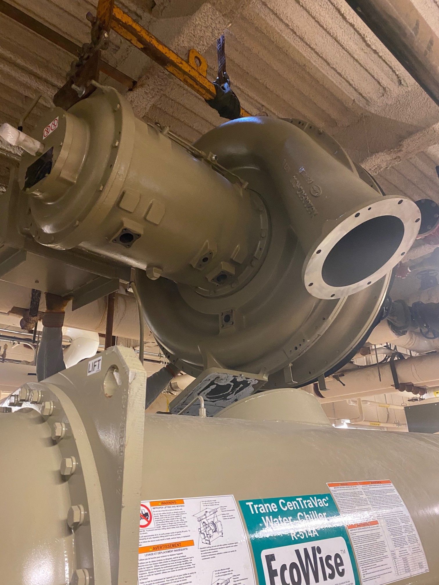 Large industrial pump being installed. Light green metal, gray ceiling.