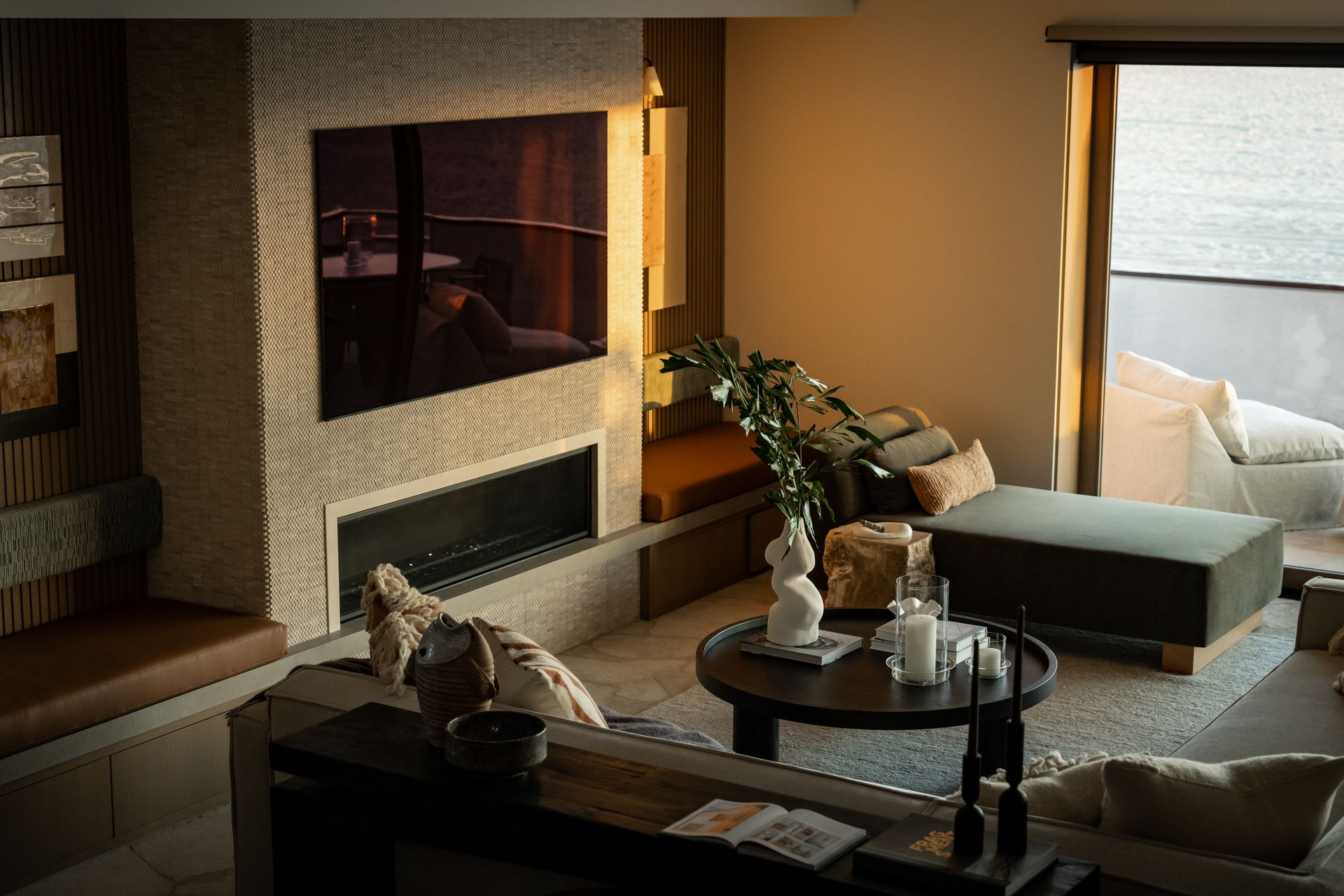 A modern, high-angle interior view of a living room featuring a stone fireplace, dark furniture, and a balcony view.