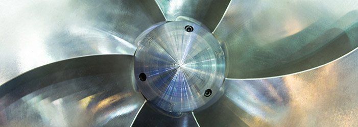 Close-up of a shiny metal propeller with five blades, viewed from the center.