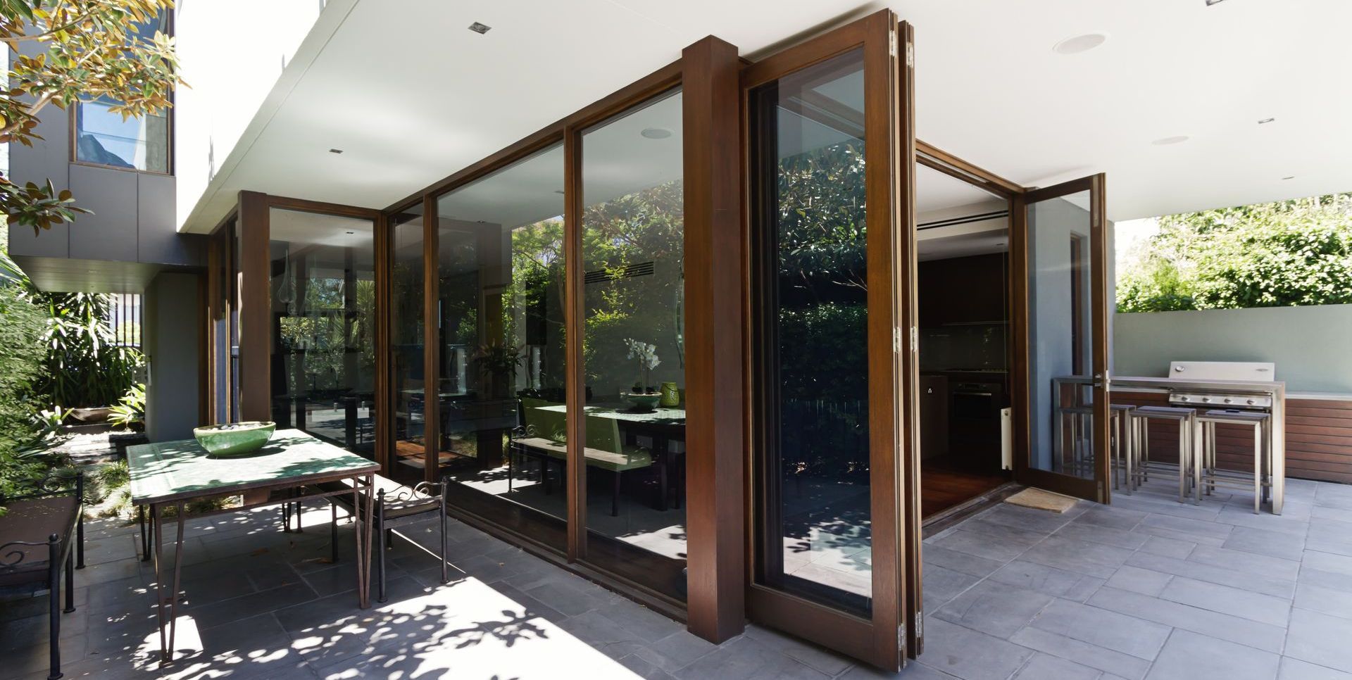 Exterior view of a modern home with open glass doors leading to an outdoor patio.