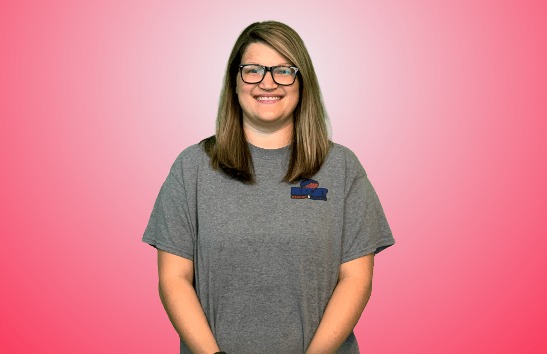 A person wearing glasses and a gray t-shirt with a logo, smiling against a pink background.