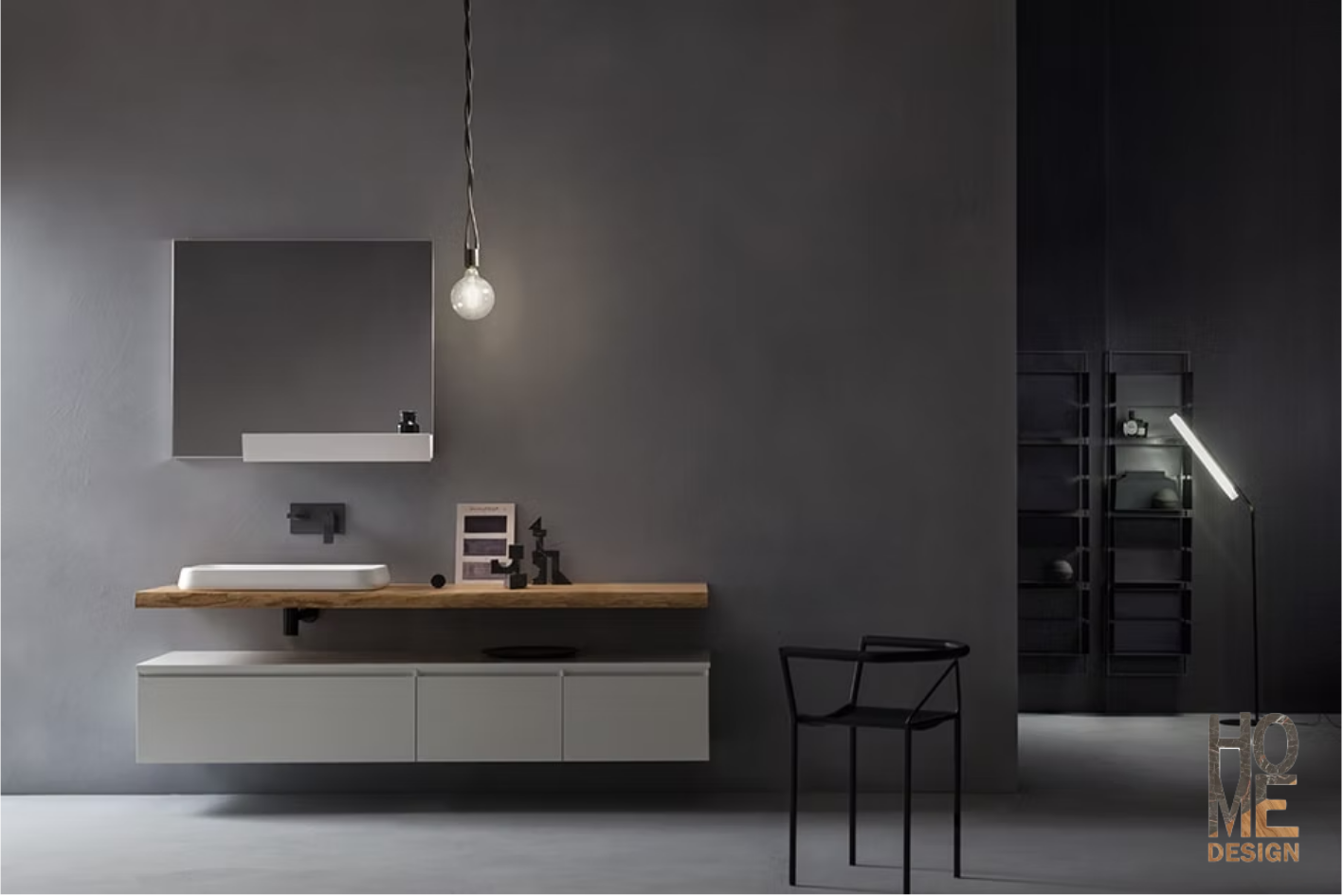 Mobile bagno minimalista di colore grigio con specchio, lampada a sospensione e sedia nera, su uno sfondo scuro.