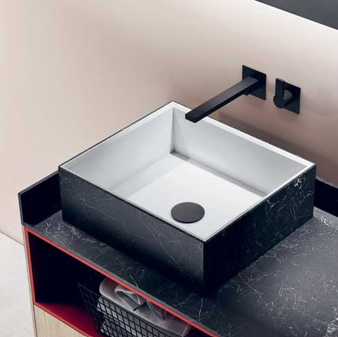 Lavabo quadrato bianco con rubinetto nero su un piano di lavoro scuro in un bagno moderno.