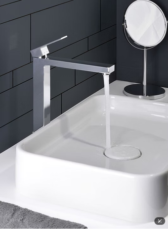 Rubinetto cromato moderno sopra un lavabo bianco con specchio rotondo in un bagno piastrellato di scuro