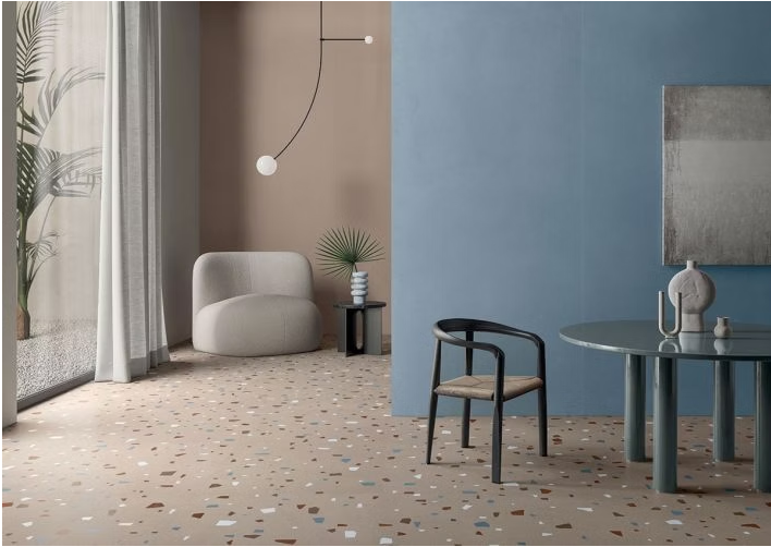 Soggiorno moderno con pareti blu e beige, poltrona curva, tavolino e pavimento decorato.